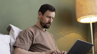 young-man-using-laptop-bed